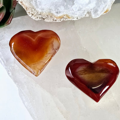 Carnelian Crystal Hearts - You Choose #2 both variants on stone platter with props and plants in the background