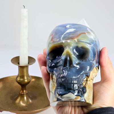 Lava Agate Crystal Skull Carving - One-of-a-Kind in hand for size reference with candle in the background