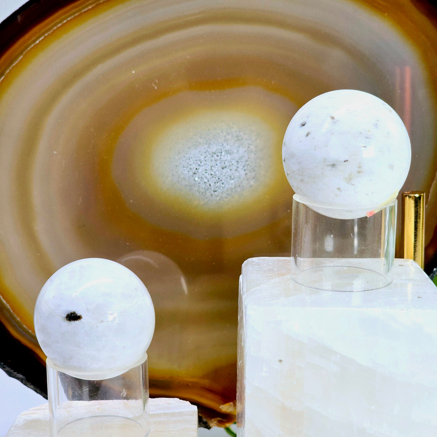 Scolecite Crystal Sphere - You Choose both variants on acrylic sphere stands on onyx platforms with natural agate slice in the background