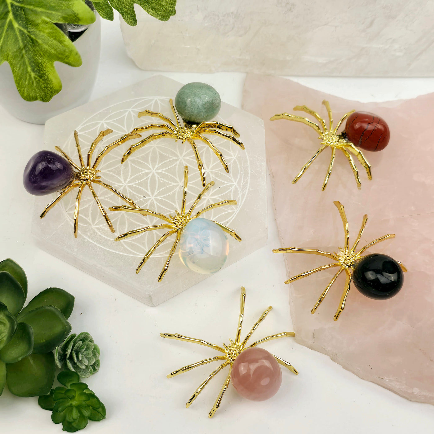 Crystal Spider - Gold-Toned Metal Spider with Tumbled Stone Body - You Choose Stone all variants on stone platters with props and plants in the background