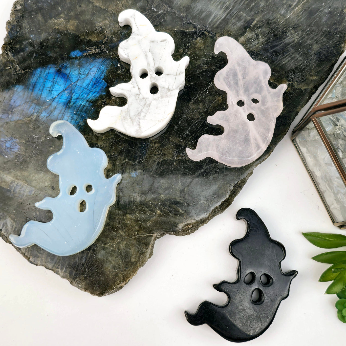 Crystal Ghost with Hat Carving - Halloween Decor - You Choose Stone - all variants top view on stone platters and white surface with props and plants in the background