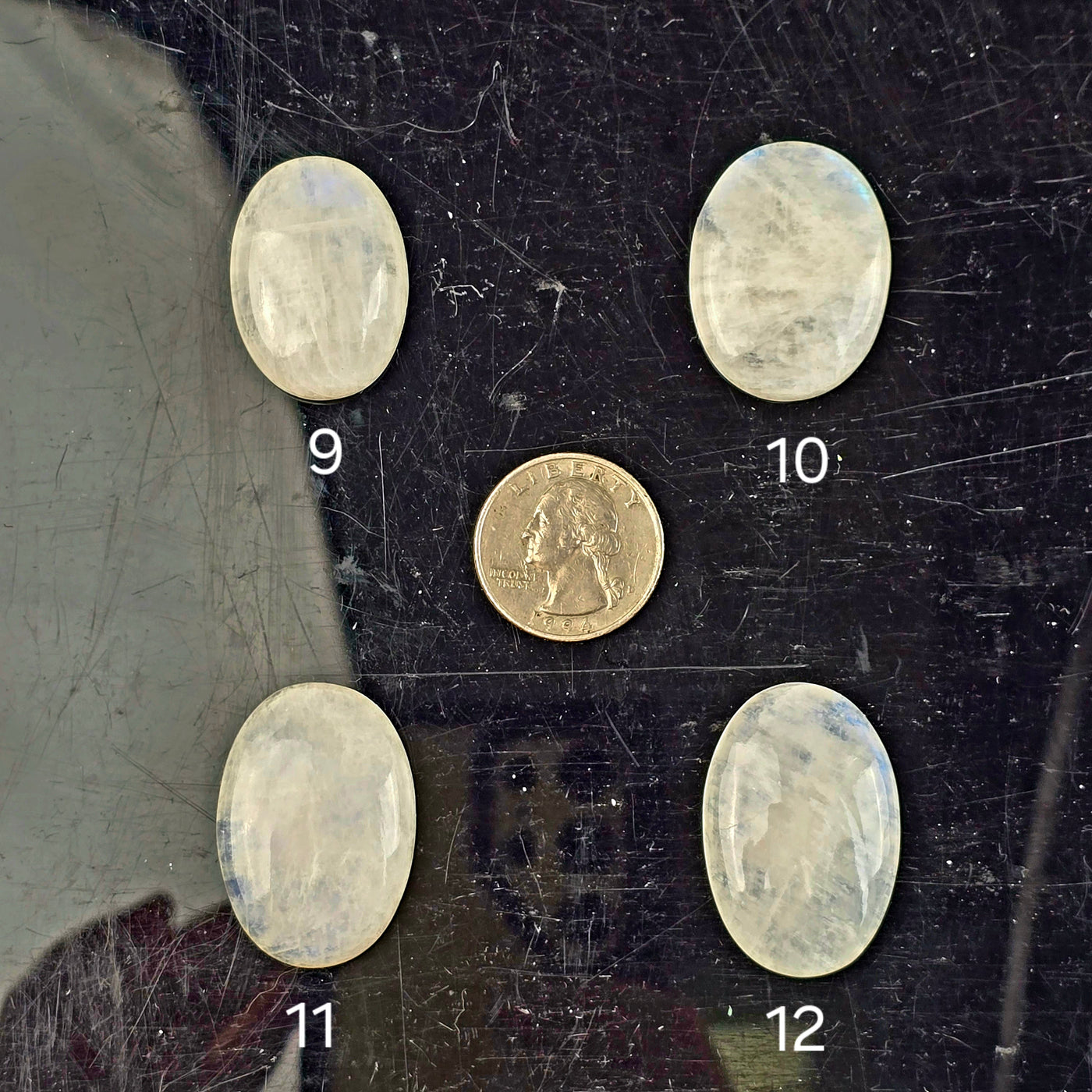 Moonstone Oval Crystal Cabochon - You Choose variants 9, 10, 11, and 12 labeled with quarter for size reference on black acrylic background