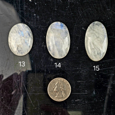 Moonstone Oval Crystal Cabochon - You Choose variants 13, 14, and 15 labeled with quarter for size reference on black acrylic background