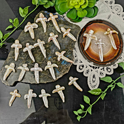 Cross Shaped Freshwater Pearl - Undrilled - You Choose all variants on labradorite platter, black acrylic, and natural agate slice on white doily with plants