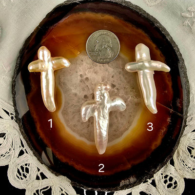 Cross Shaped Freshwater Pearl - Undrilled - You Choose variants 1, 2, and 3 labeled with quarter for size reference on natural agate slice over a white doily on black acrylic background