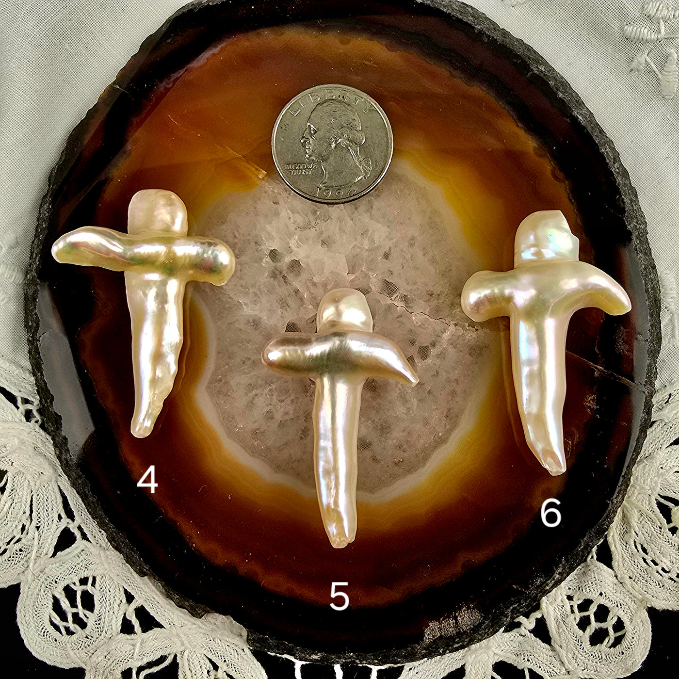 Cross Shaped Freshwater Pearl - Undrilled - You Choose variants 4, 5, and 6 labeled with quarter for size reference on natural agate slice over a white doily on black acrylic background