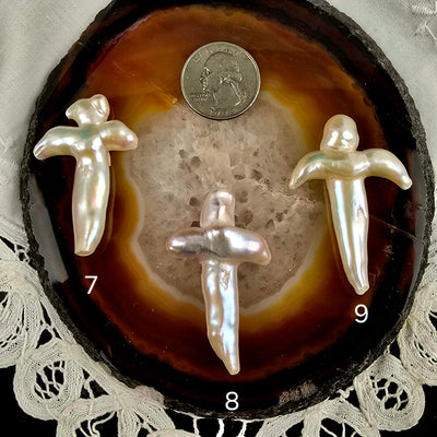 Cross Shaped Freshwater Pearl - Undrilled - You Choose variants 7, 8, and 9 labeled with quarter for size reference on natural agate slice over a white doily on black acrylic background