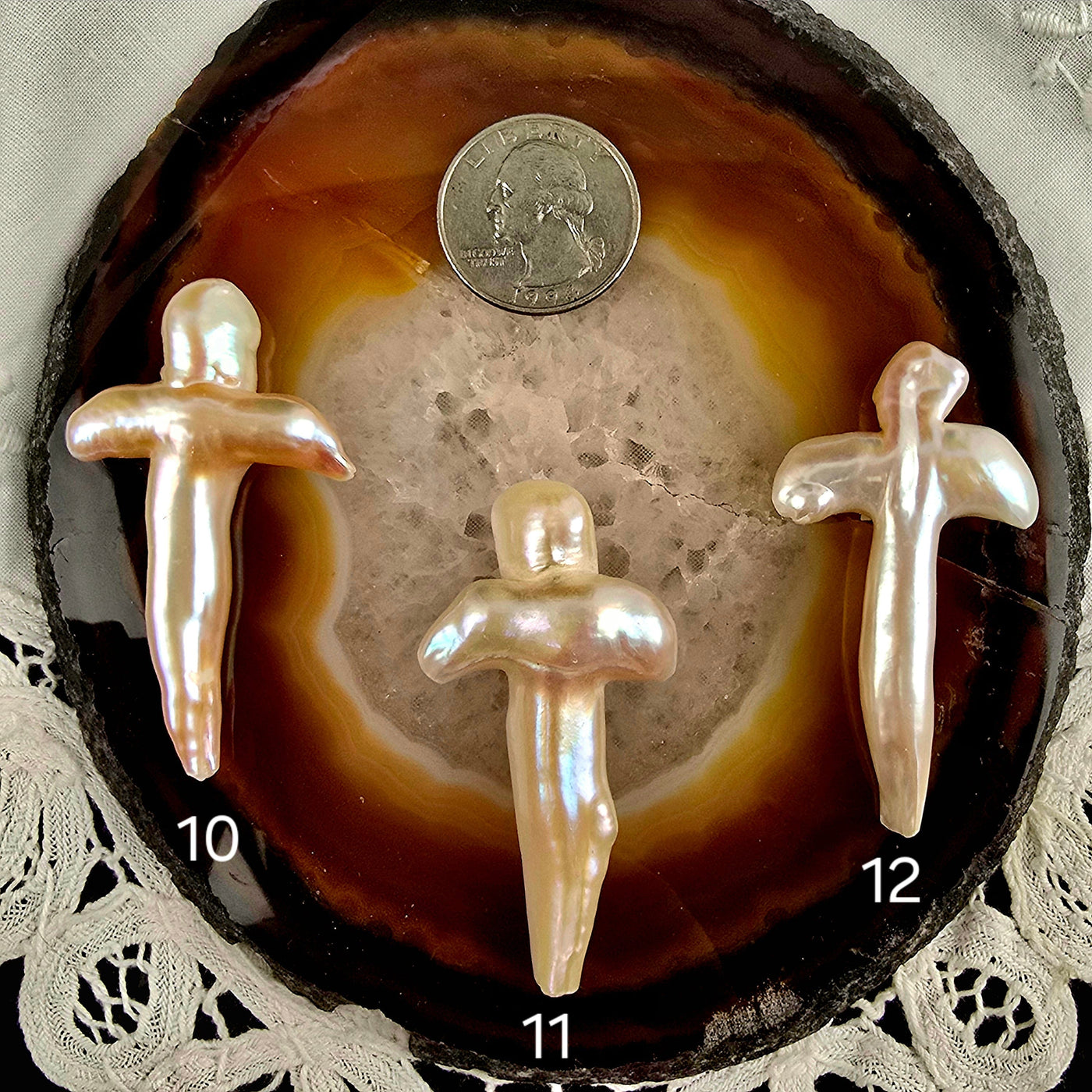 Cross Shaped Freshwater Pearl - Undrilled - You Choose variants 10, 11, and 12 labeled with quarter for size reference on natural agate slice over a white doily on black acrylic background