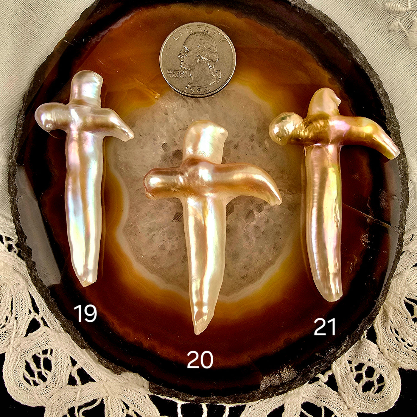 Cross Shaped Freshwater Pearl - Undrilled - You Choose variants 19, 20, and 21 labeled with quarter for size reference on natural agate slice over a white doily on black acrylic background