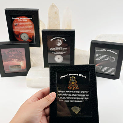 Meteorite - Libyan Desert Glass - Fulgurite - Black Framed Crystal Box Display - You Choose - Libyan Desert Glass variant in hand for size reference with other variants in the background on crystal stands with light background