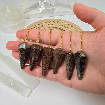 Garnet Crystal Pendulum with Gold Plated Bail and Chain - six in hand to show size reference with props in the background