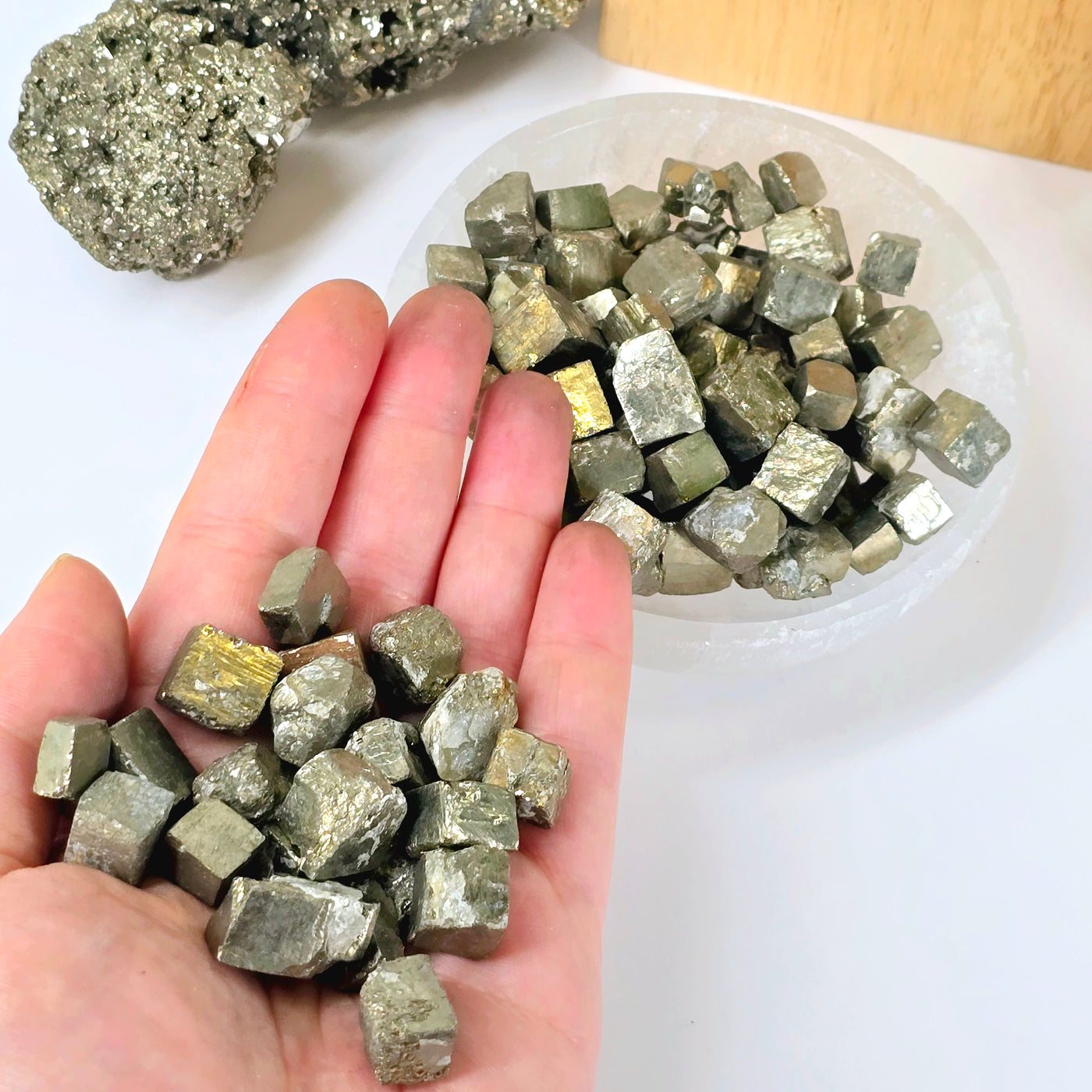 Pyrite Crystal Cubes - By the Pound - half in hand with other half in bowl with props in the background