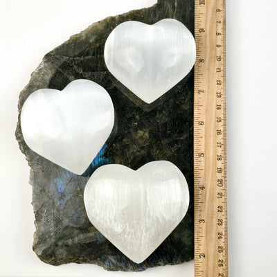 Selenite Crystal Heart - 9 cm - three with ruler for size reference on labradorite platter on white background