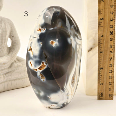 Orca Agate Polished Freeform Cut Base - You Choose variant 3 labeled with ruler for size reference next to Buddha statue