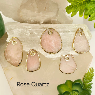 Crystal Freeform Slice Pendant with 24k Gold Electroplated Edges Top Front Drilled - You Choose Stone - rose quartz variant labeled on stone platters with props and plants in the background