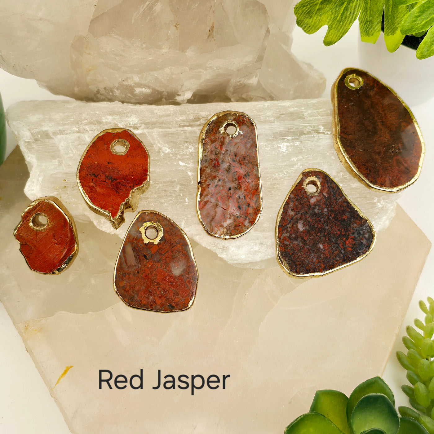 Crystal Freeform Slice Pendant with 24k Gold Electroplated Edges Top Front Drilled - You Choose Stone - red jasper variant labeled on stone platters with props and plants in the background