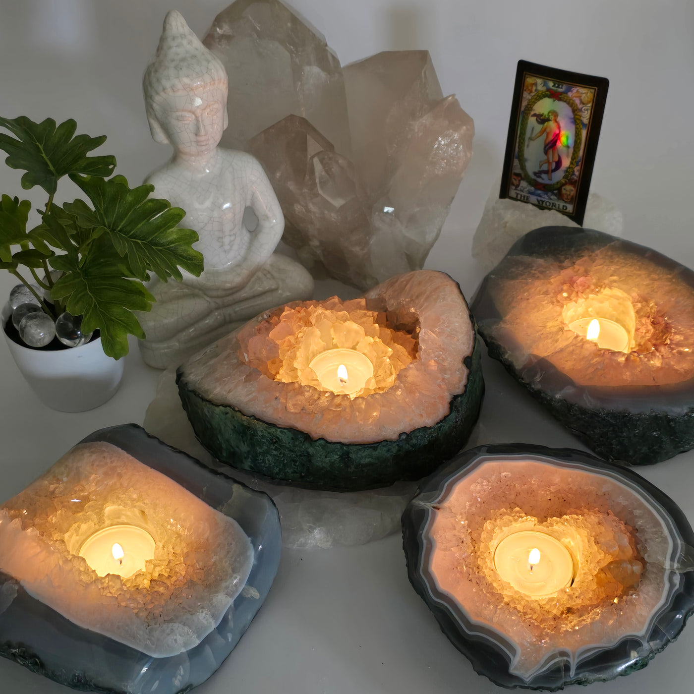 Crystal Geode Semi Polished Candle Holder - You Choose all variants with candles lit in dim lighting with props and plants in the background