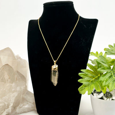 Citrine Natural Rough Crystal Point Pendant with 24k Gold Electroplated Cap and Bail one on necklace stand with chain and props and plants in the background