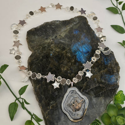 Chalcedony Druzy Galaxy Pendant Sterling Silver Necklace with Druzy and Mother-of-Pearl Stars and Crystal Quartz Moon Charms - Handmade - One-of-a-Kind on labradorite platter with plants in the background