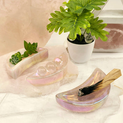 Angel Aura Rose Quartz Moon Bowls - You Choose #1 three showing examples of usage, one with plants, one with quartz spheres, and another with a burnt palo santo stick with plants and props in the background