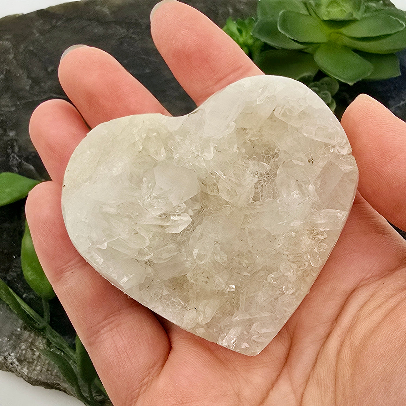 Crystal Quartz Cluster Heart - One-of-a-Kind in hand for size reference with props and plants in the background