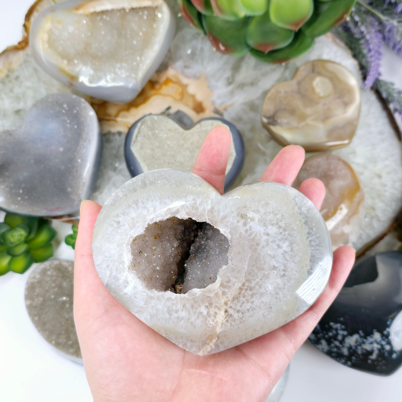 Agate Druzy Crystal Heart YOU CHOOSE #2 variant 8 in hand for size reference with other variants in the background with props and plants