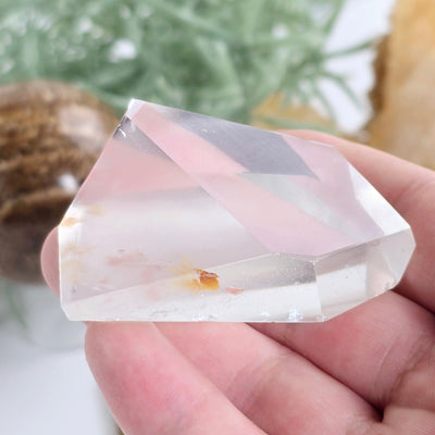 Cat's Eye Quartz - Crystal Quartz Freeform - One-of-a-Kind in hand for size reference with props and plants in the background