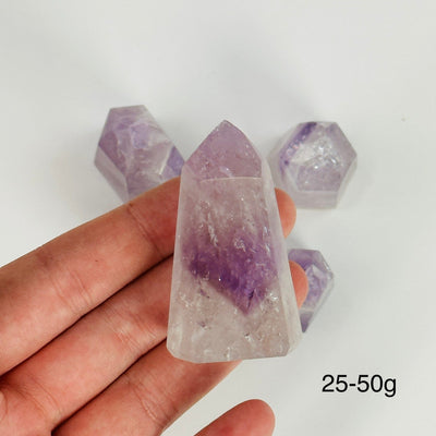 hand holding up 25-50g amethyst polished points with decorations in the background