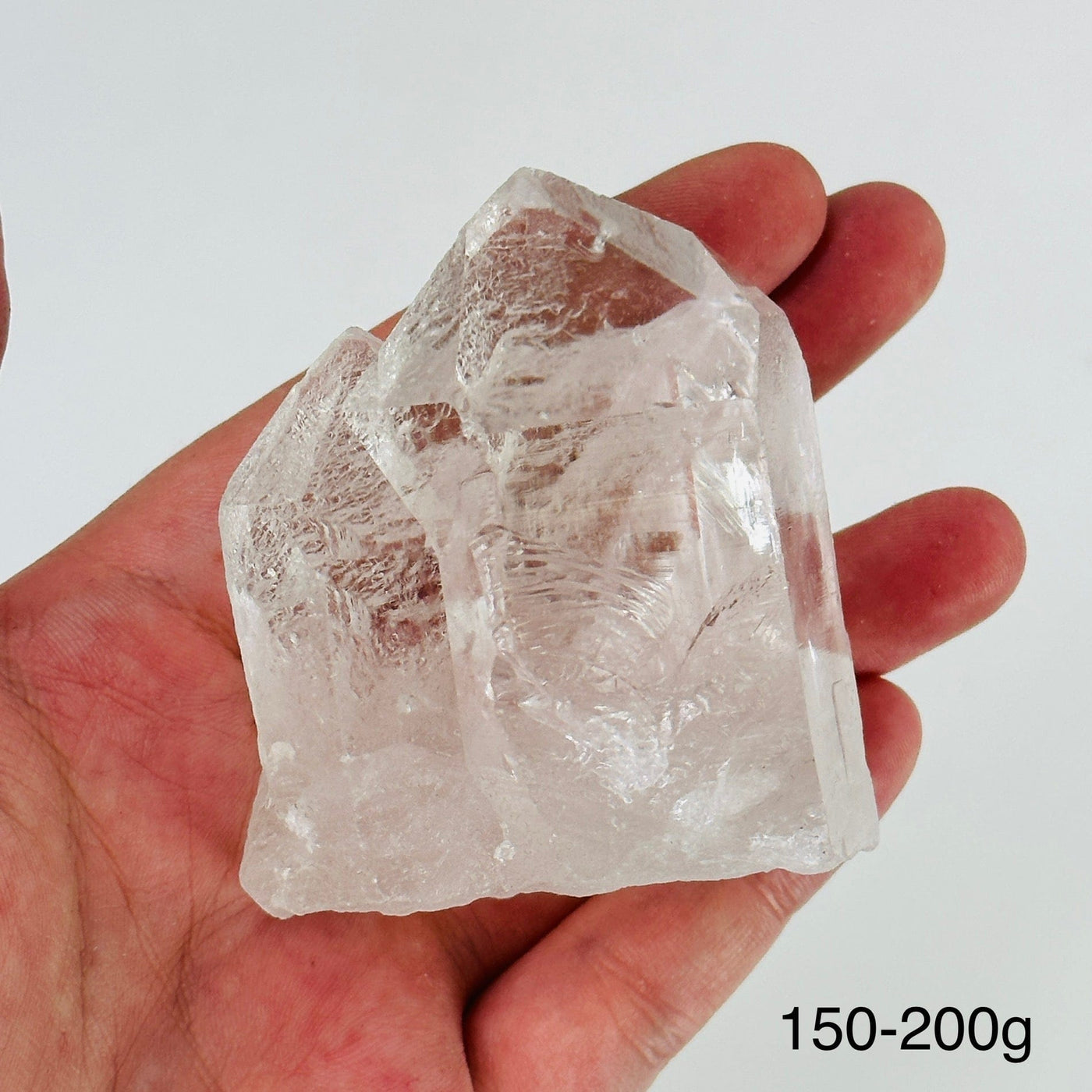 hand holding up crystal quartz point on white background
