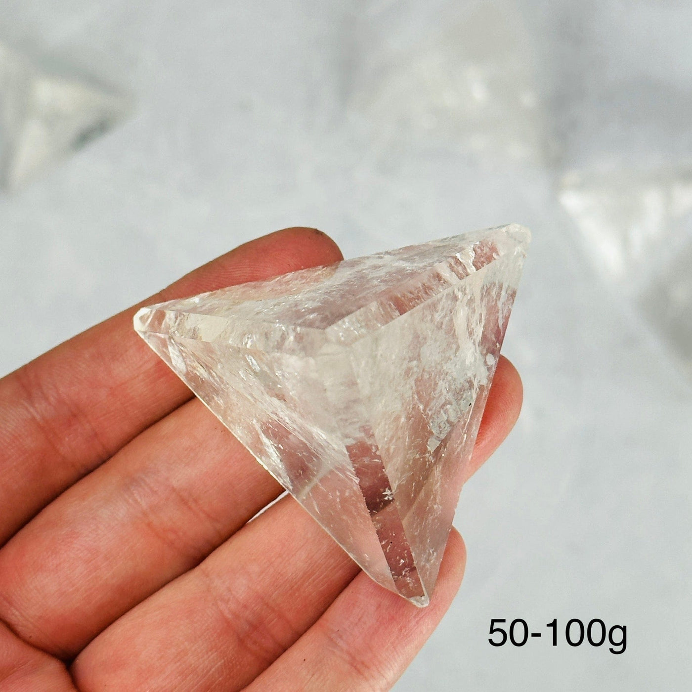 hand holding up 50-100g crystal quartz pyramid