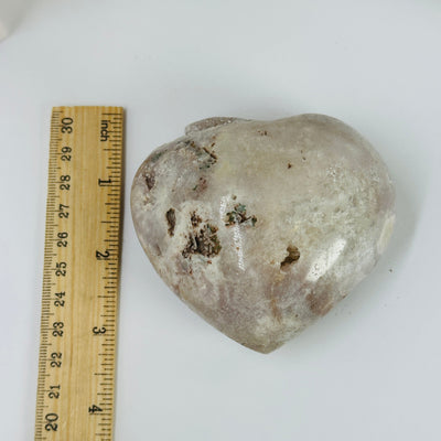 pink amethyst heart next to a ruler for size reference