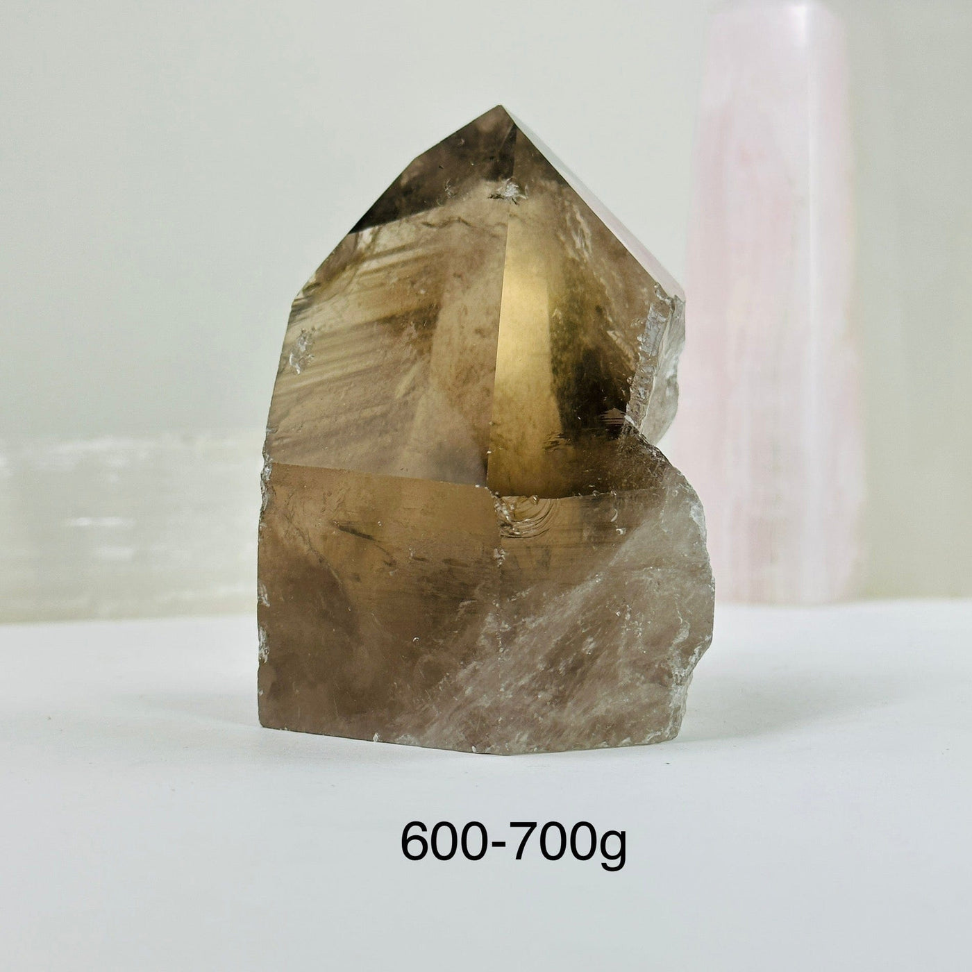 600-700g smoky quartz semi polished point with decorations in the background