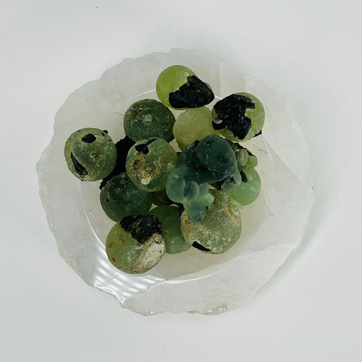 bowl filled with epidote with prehnite clusters on white background