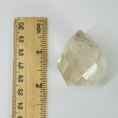 citrine faceted point next to a ruler for size reference