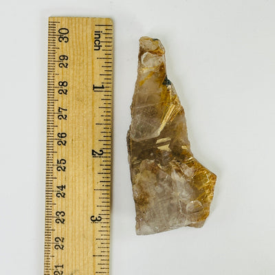 rutilated quartz next to a ruler for size reference