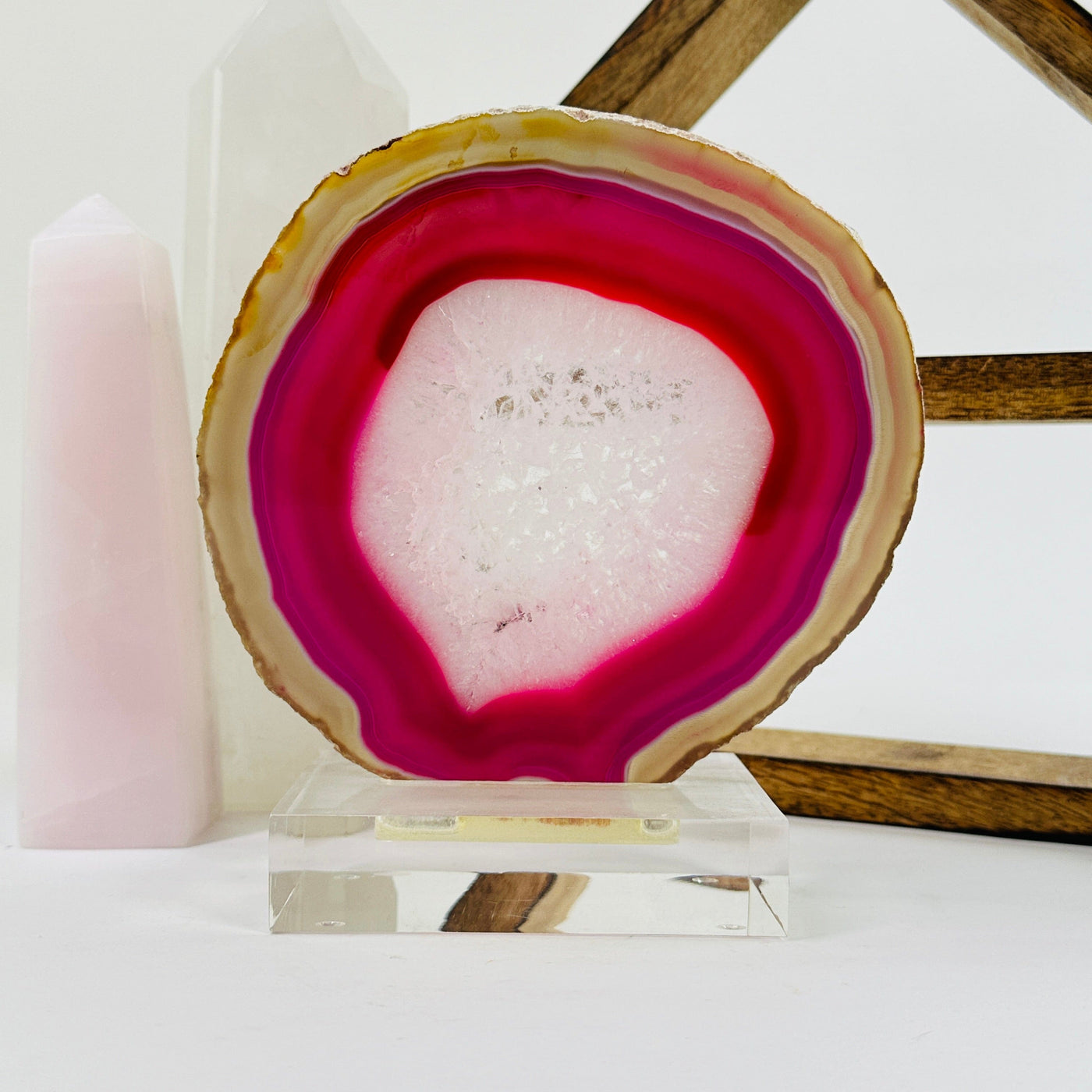 Pink agate slice on acrylic stand with decorations in the background