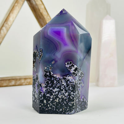 purple dyed agate druzy point with decorations in the background