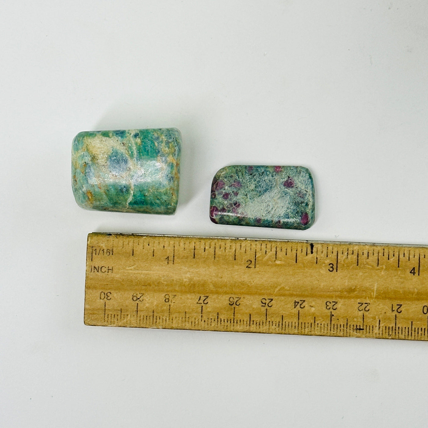 ruby fuchsite tumbled stones next to a ruler for size reference