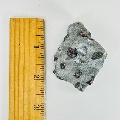 hematite with garnet next to a ruler for size reference