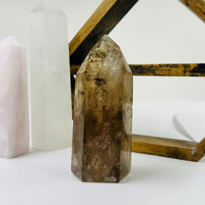 smokey quartz point with decorations in the background