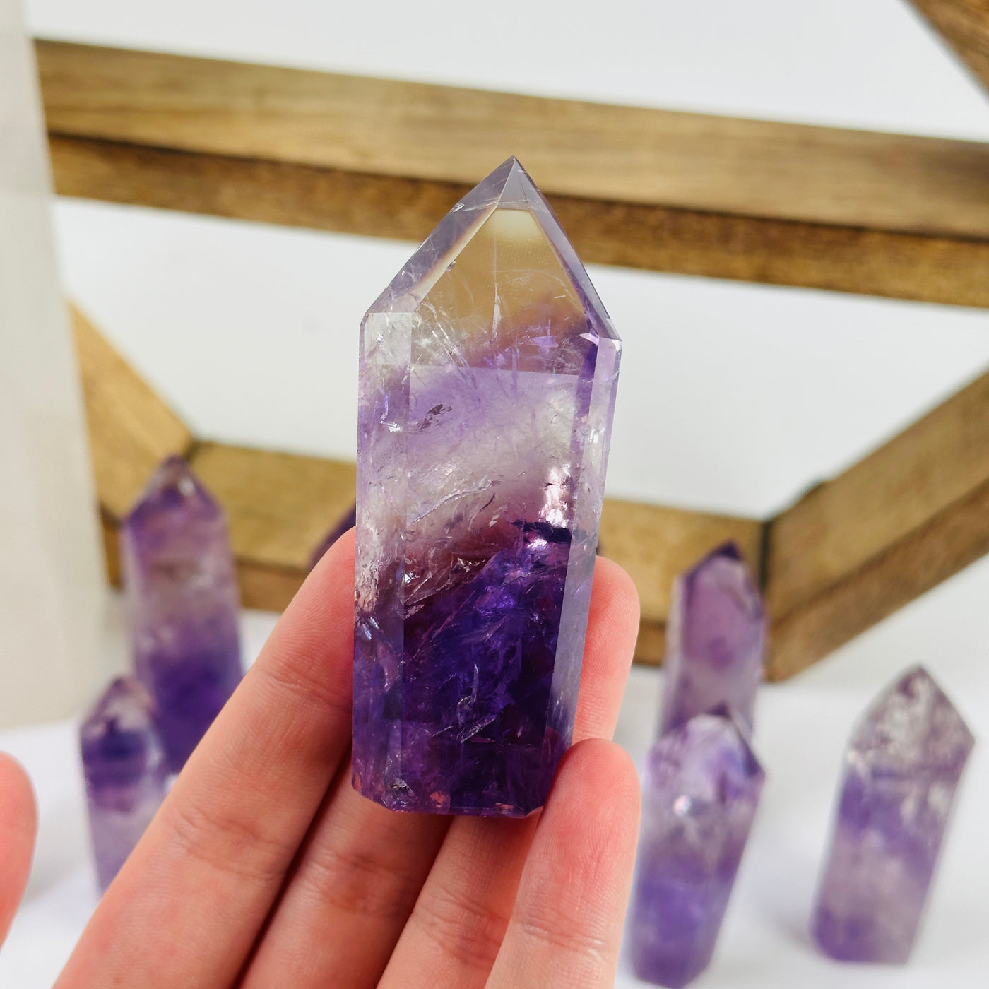 fingers holding up amethyst point with decorations in the background