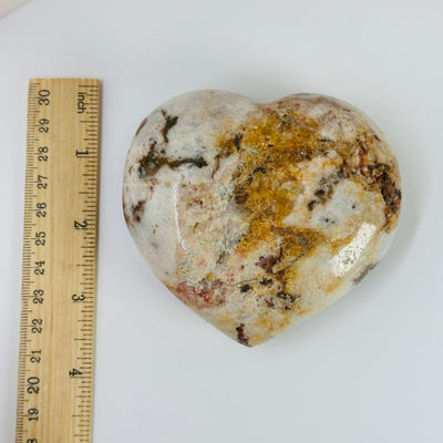 pink amethyst heart next to a ruler for size reference