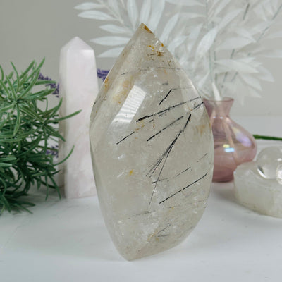 Golden Healer Quartz with Black Tourmaline - Crystal Flame Point Cut Base - One-of-a-Kind #3 front view with props and plants in the background