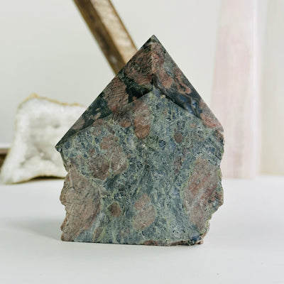 rhyolite semi polished point with decorations in the background