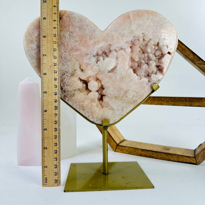 pink amethyst hearts on metal stand next to a ruler for size reference