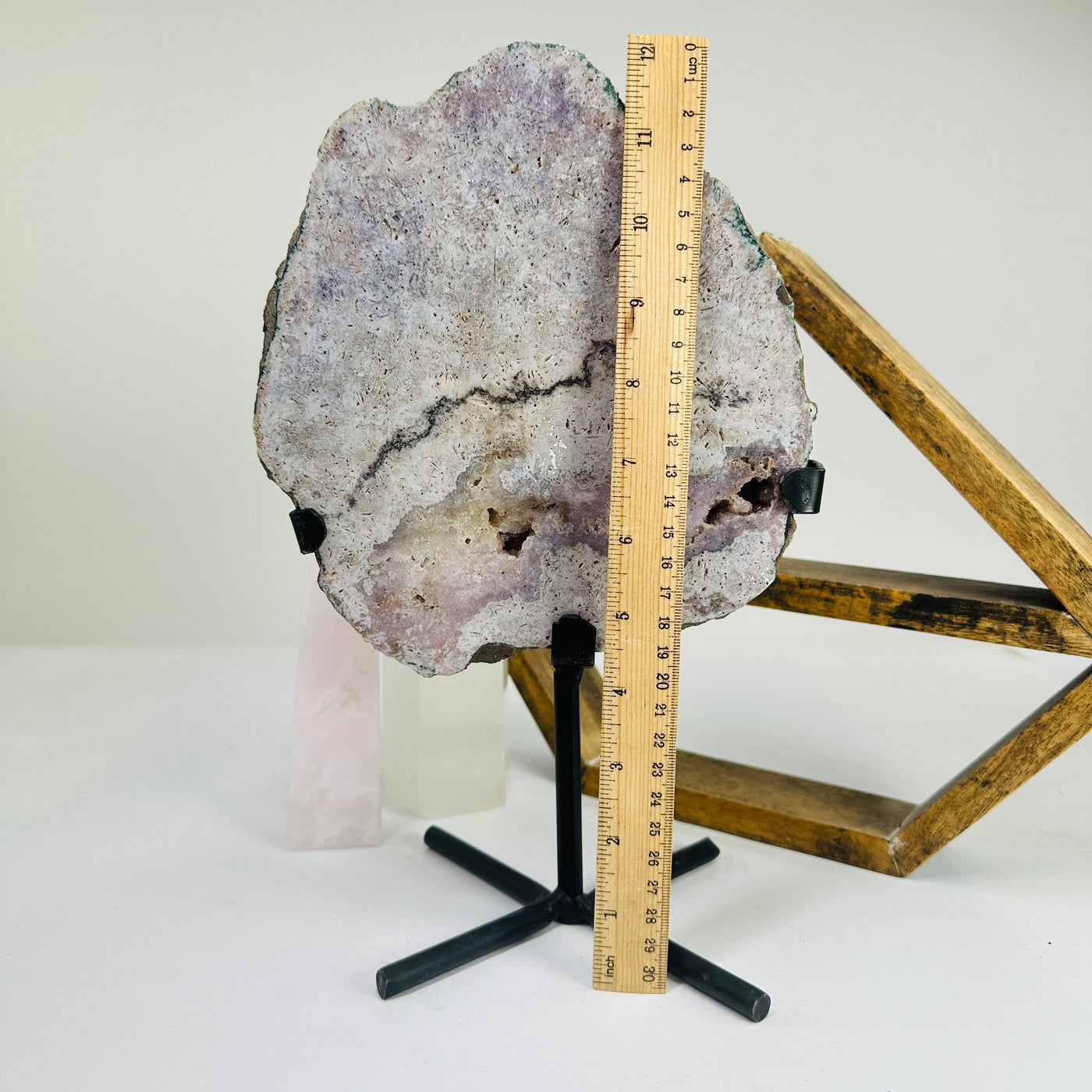 pink amethyst on metal stand next to a ruler for size referece