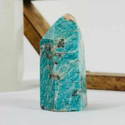 Amazonite polished point with decorations in the background