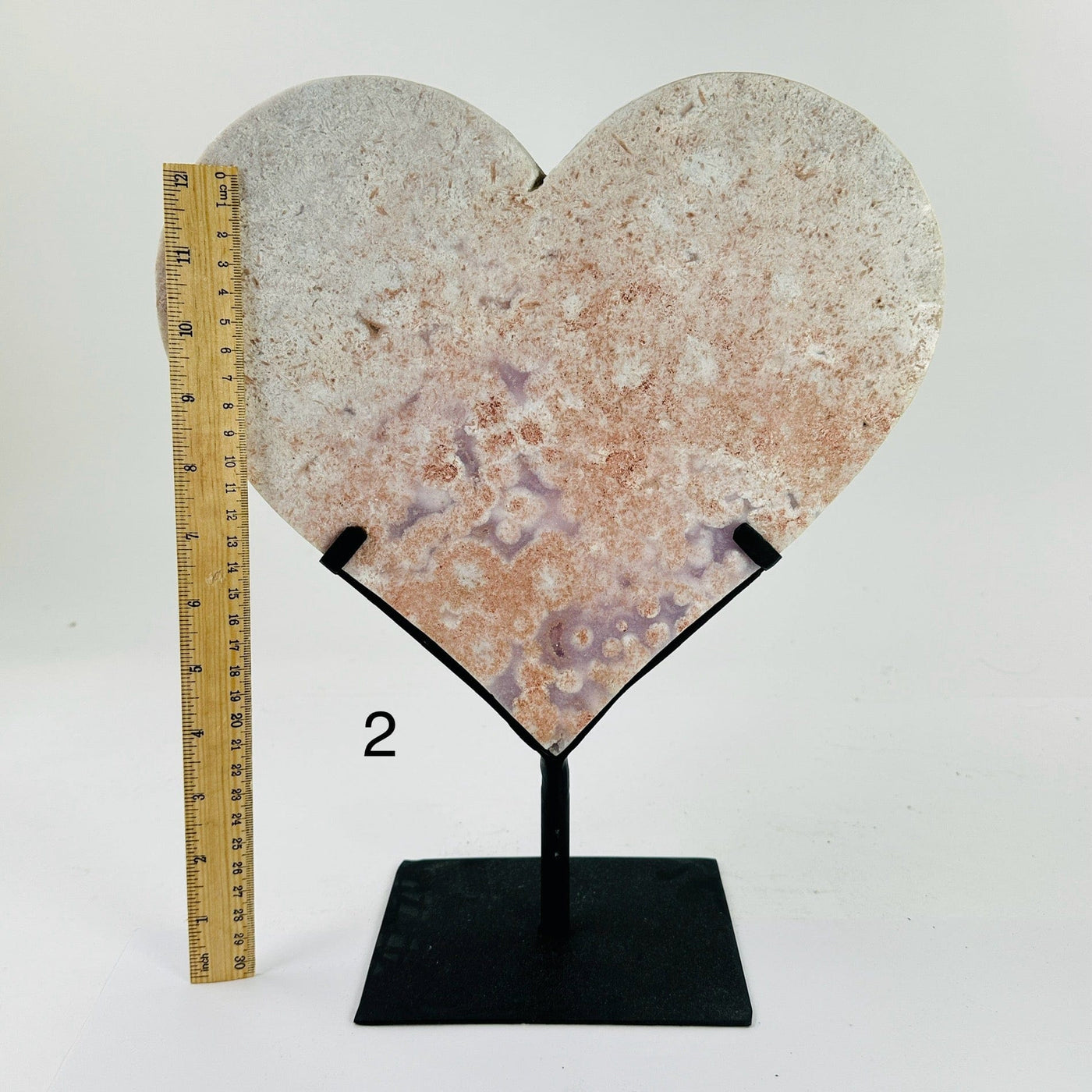 pink amethyst heart on metal stand next to a ruler for size reference