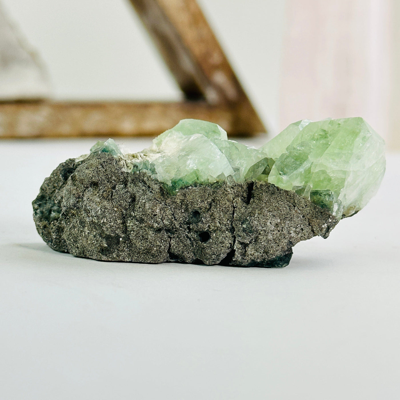 green apophyllite on matrix cluster with decorations in the background