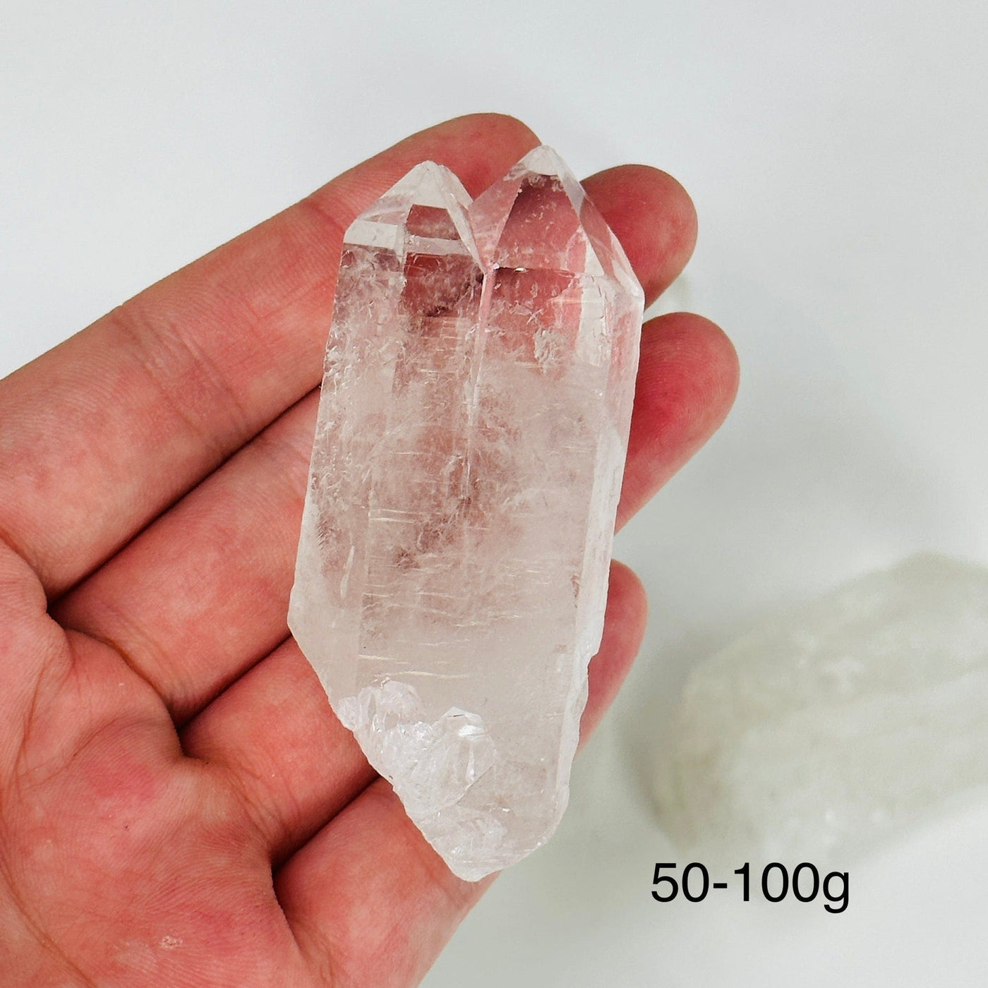 hand holding up crystal quartz point with others in the background